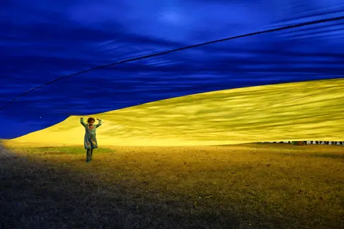 Haley Romero, 6, stands beneath a massive Ukrainian flag held by demonstrators as they rally in support of Ukraine during a protest on the Ellipse near the White House in Washington, D.C., U.S., March 8, 2025. REUTERS/Craig Hudson