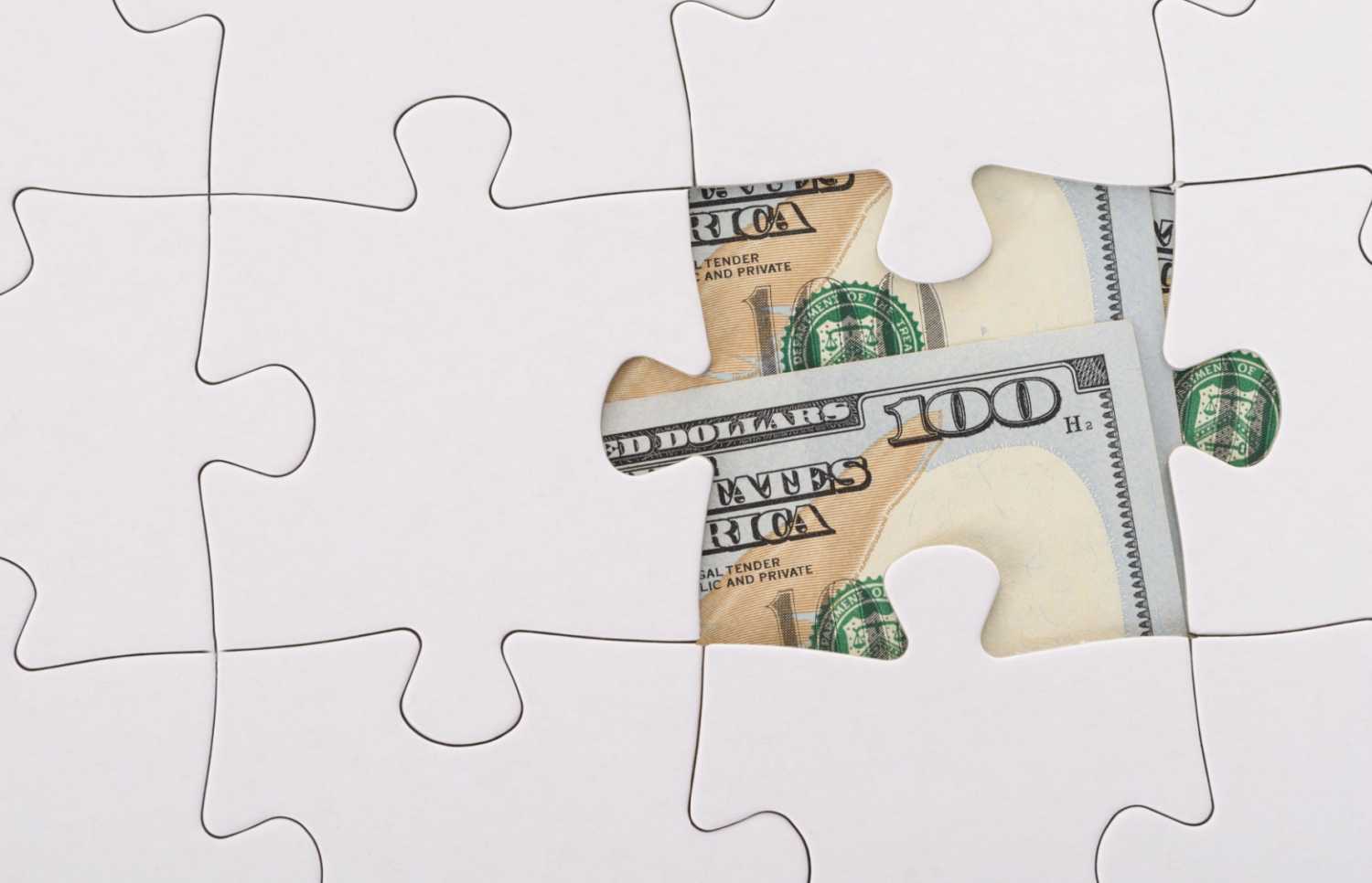 An all-white jigsaw puzzle missing one piece; a hundred dollar bill peeks through from behind. The image evokes uncertainty, an attempt to piece together a whole picture with vague and uncertain information, as well as the psychological impact of personal finance on everyday life.