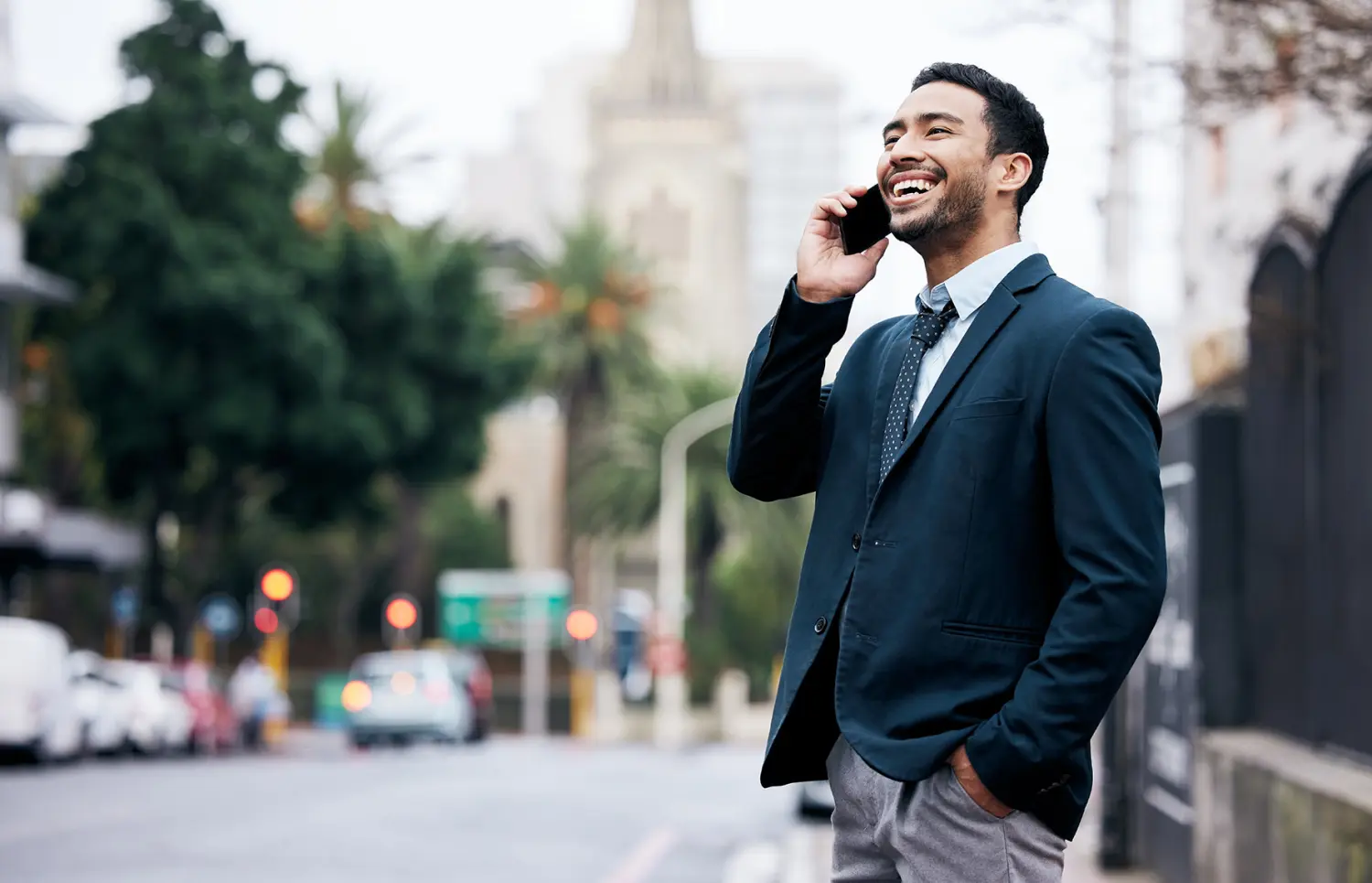 Hispanic or Latino businessman standing in the city and using his cellphone.