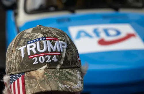 A participant wears a cap with the words ""Trump 2024"" while sitting in front of a car with an AfD print. A new state parliament will be elected in Thuringia on September 1, 2024.