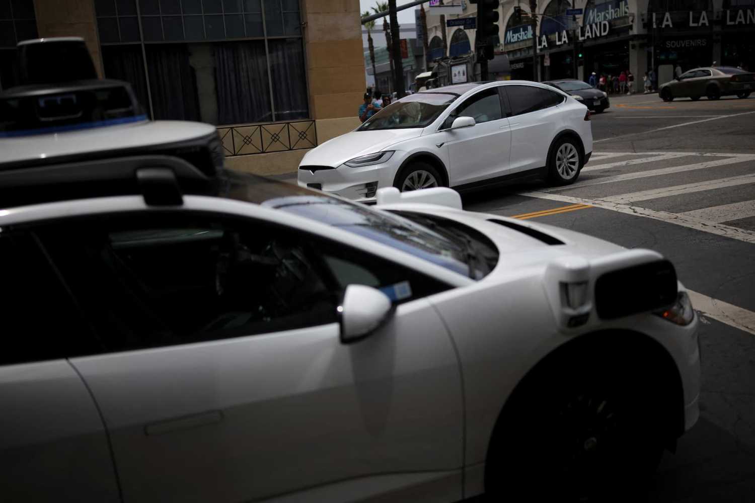 A Tesla drives by a Waymo self-driving car in Los Angeles, California, U.S., May 12, 2025.