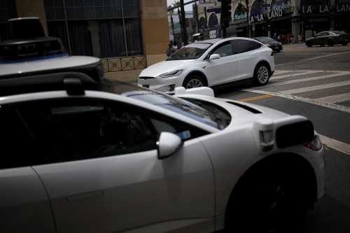A Tesla drives by a Waymo self-driving car in Los Angeles, California, U.S., May 12, 2025.