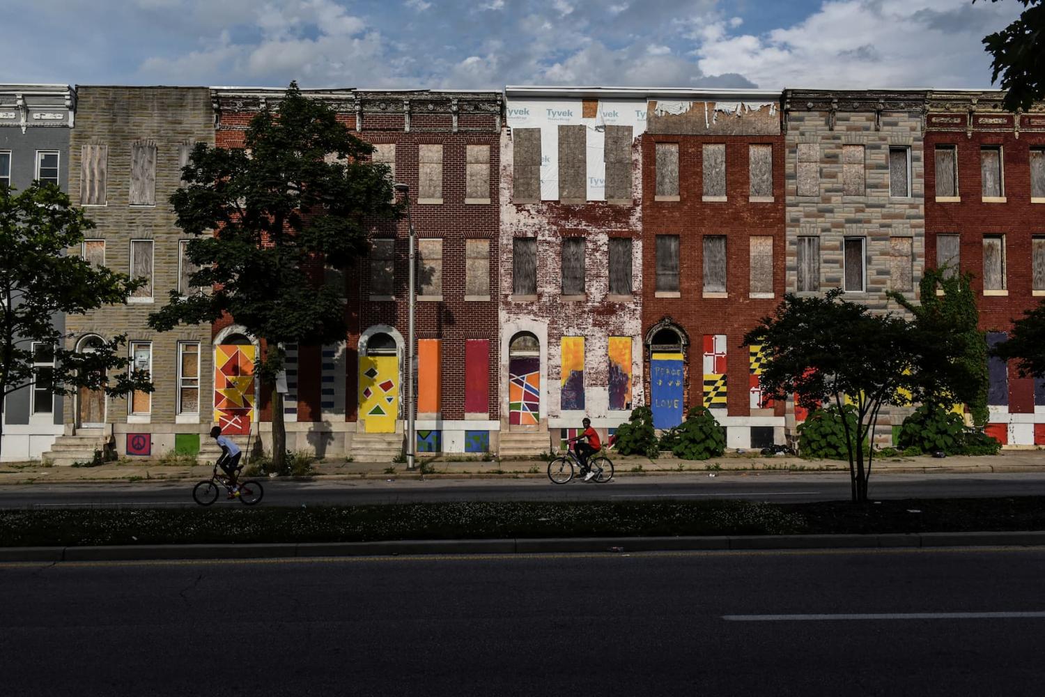 Young boys ride their bikes past boarded-up and abandoned row of houses in Baltimore, Maryland, U.S., May 26, 2019.