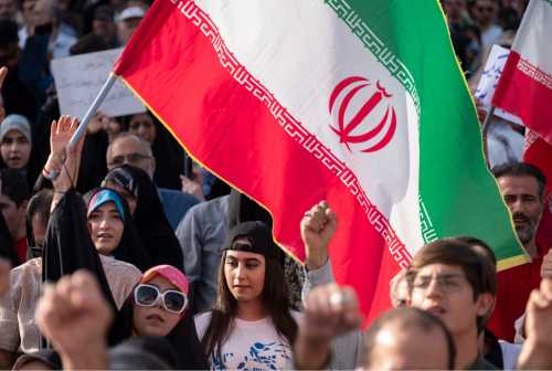 A young Iranian woman looks on while protesters shout anti-U.S. and anti-Israeli slogans during a protest to condemn the U.S. attacks on Iran's nuclear facilities in downtown Tehran, Iran, on June 22, 2025, amid the Iran-Israel war. (Photo by Morteza Nikoubazl/NurPhoto)
