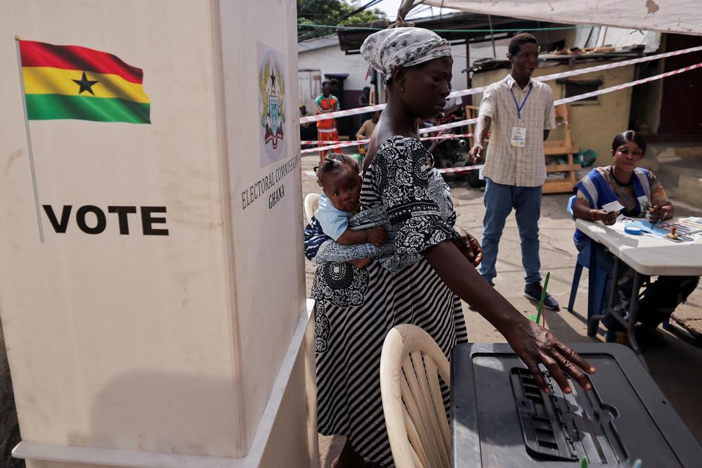 A woman carries a child as she votes at a polling station during the presidential and parliamentary election in Accra, Ghana, December 7, 2024.