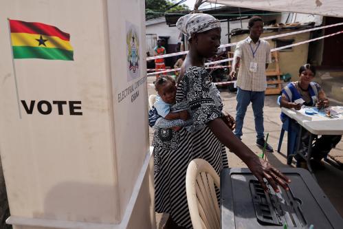 A woman carries a child as she votes at a polling station during the presidential and parliamentary election in Accra, Ghana, December 7, 2024.