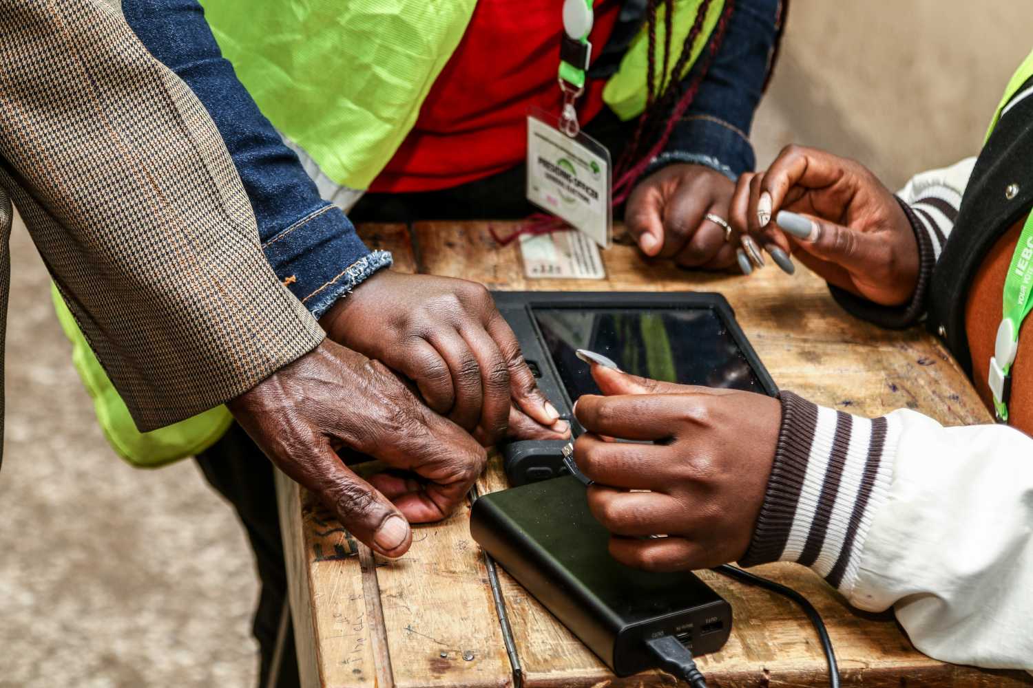 Election officials confirm a voter's biometric details using a biometric voter register device