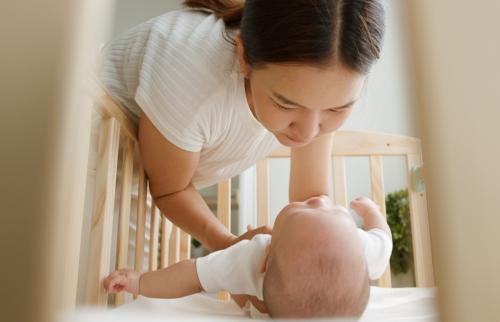 Mother putting her baby in a crib