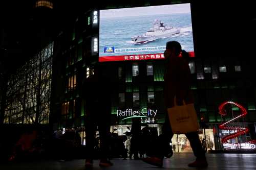A Chinese navy vessel is seen on a giant screen showing news footage about joint army, navy, air and rocket forces drills around Taiwan by the Chinese People's Liberation Army (PLA), outside a shopping mall in Beijing, China, April 1, 2025.