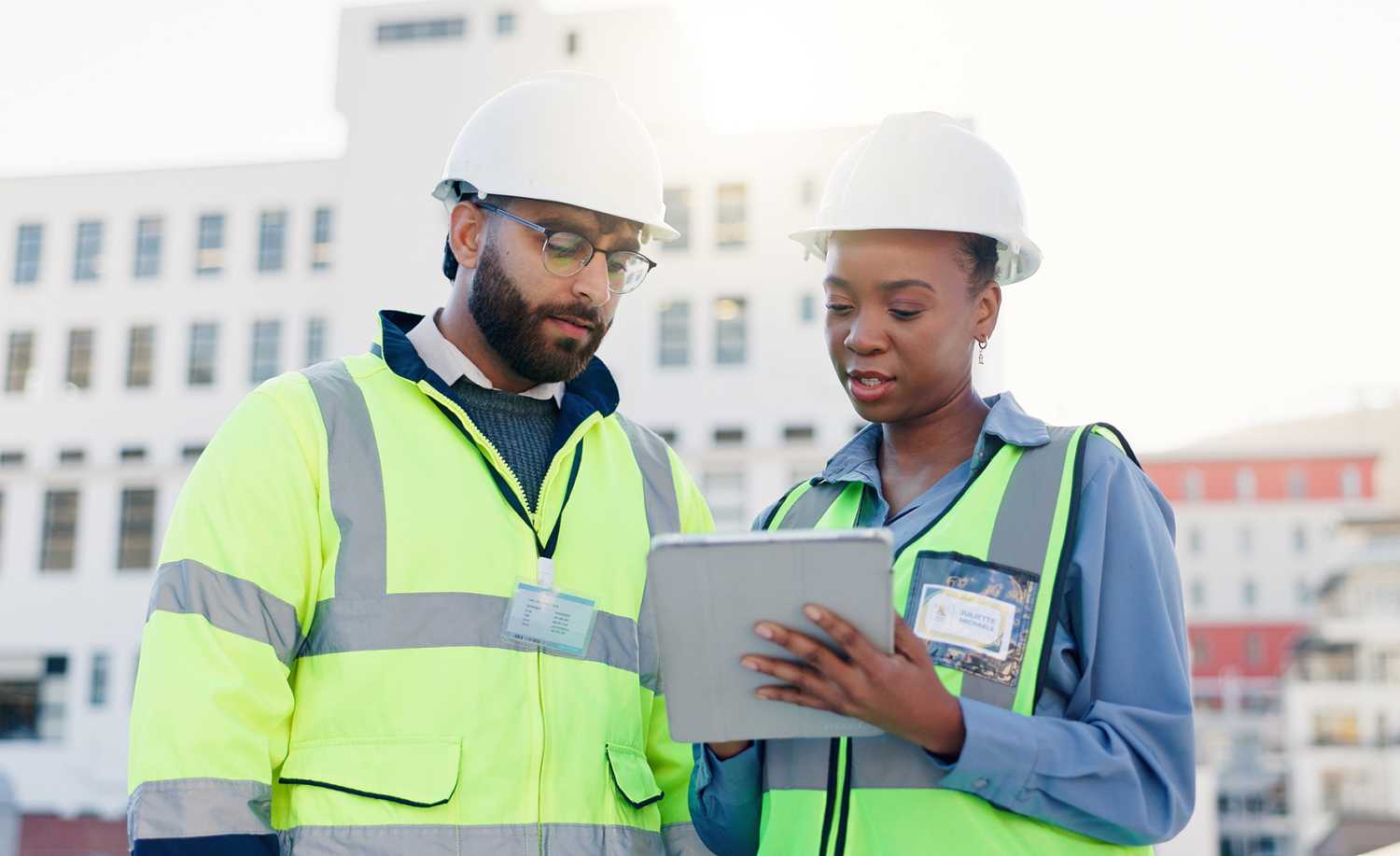 Business people, architect and discussion with tablet on rooftop for construction or planning in city. Contractors, colleagues or civil engineers with technology for industrial infrastructure in town