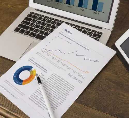 A printed document with charts on top of an open laptop.