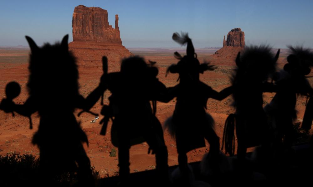 Kachina dolls line a window in a gift shop as the sun sets on Monument Valley in the Navajo Nation, Arizona