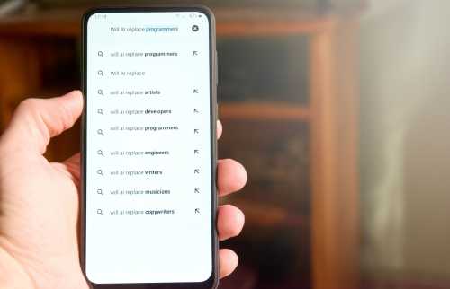 Hand holding phone with search query on screen, "Will AI replace programmers?"