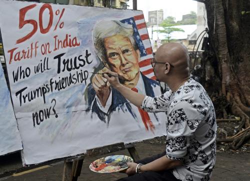 An artist paints a protest artwork depicting former U.S. President Donald Trump in Mumbai, India, on August 7, 2025, following reports of a proposed 50% tariff on Indian imports by the United States. The banner questions the reliability of diplomatic ties amid escalating trade tensions.