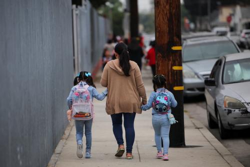 A parent and students arrive for the first day of school, as teachers and volunteers patrol for the presence of Immigration and Customs Enforcement (ICE), at the Ninety-Third Street Elementary School, in Los Angeles, California, U.S., on August 14, 2025.