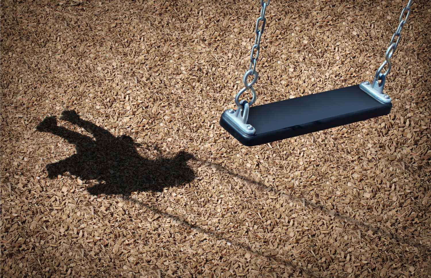 Shadow of a child on a swing on a playground.