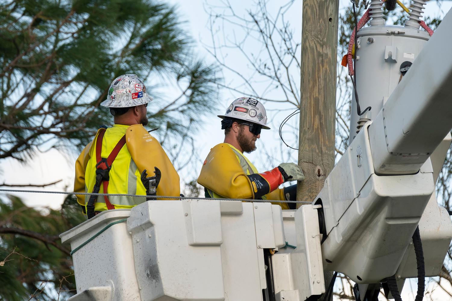 Electrician workers repairing damaged power lines using bucket trucks after hurricane in Florida residential area. North Port, USA - October 4, 2022.