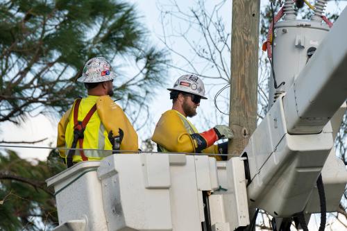 Electrician workers repairing damaged power lines using bucket trucks after hurricane in Florida residential area. North Port, USA - October 4, 2022.