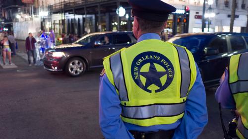 NEW ORLEANS, LOUISIANA - FEBRUARY 9, 2018 - Local police officer standing guard along Hermes Parade route for Mardi Gras celebration on February 9, 2018 in New Orleans, Louisiana.