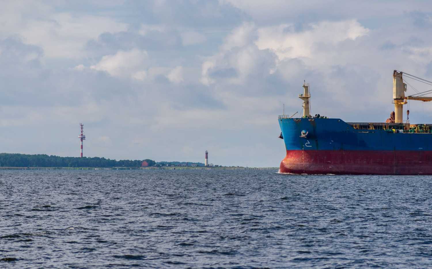 View of the front half of an oil tanker floating in front of an oil facility