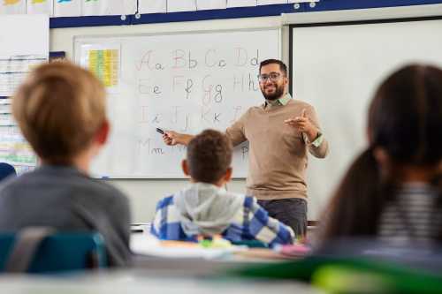 Young male teacher helping students learn the alphabet.