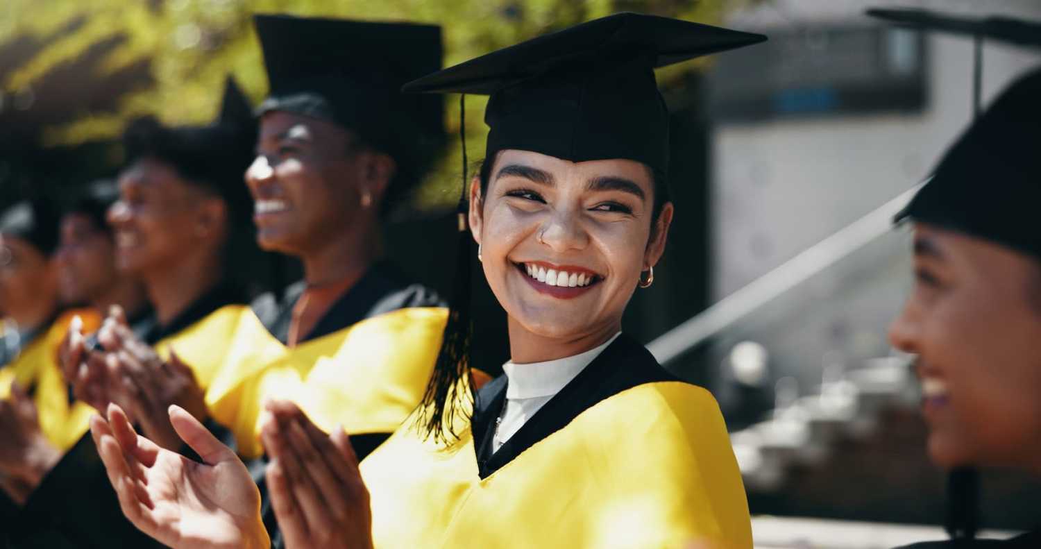 A woman joins students in celebrating their graduation.