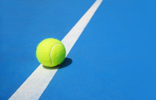 Tennis ball on the line of a tennis court.