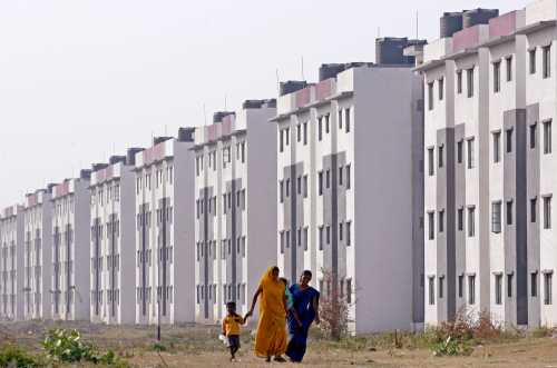 Residents walk past a block of state-funded flats for slum dwellers previously living in low-lying, flood-prone areas in the western Indian city of Surat November 24, 2009.