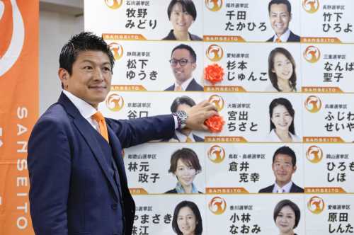 Sohei Kamiya, head of the opposition Sanseito party, attaches a rosette to the name of a party candidate assured of victory in the House of Councillors election in the early hours of July 21, 2025, in Tokyo.