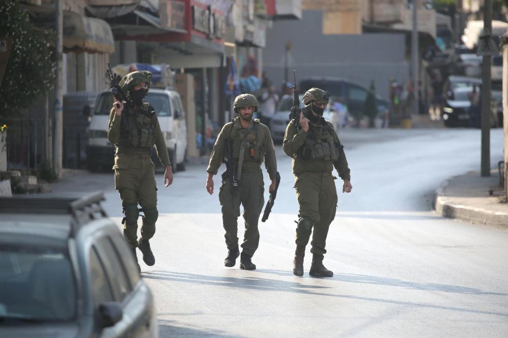 Three Israeli soldiers walk down the street in the Palestinian city of Nablus.