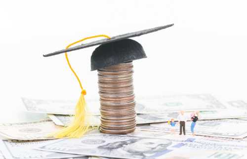Stack of coins with graduation cap and small figures of a family.