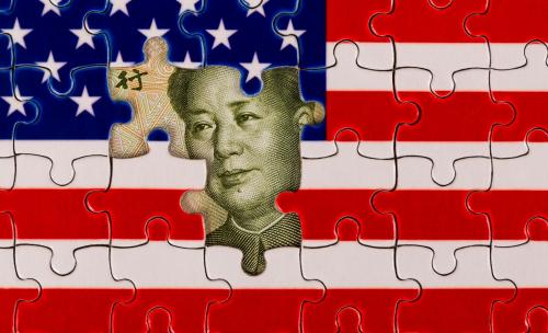 The face of Mao Zedong on the Chinese yuan peaks out from under puzzle pieces making up the U.S. flag
