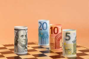 Rolled US dollar and euro notes on a chess board