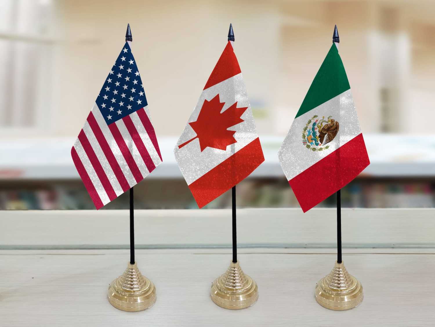 The flags of the United States, Canada, and Mexico stand side by side on a table