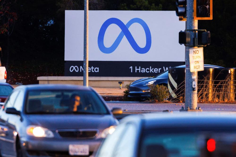 Cars drive in front of a large sign with Meta's logo, a blue infinity sign.