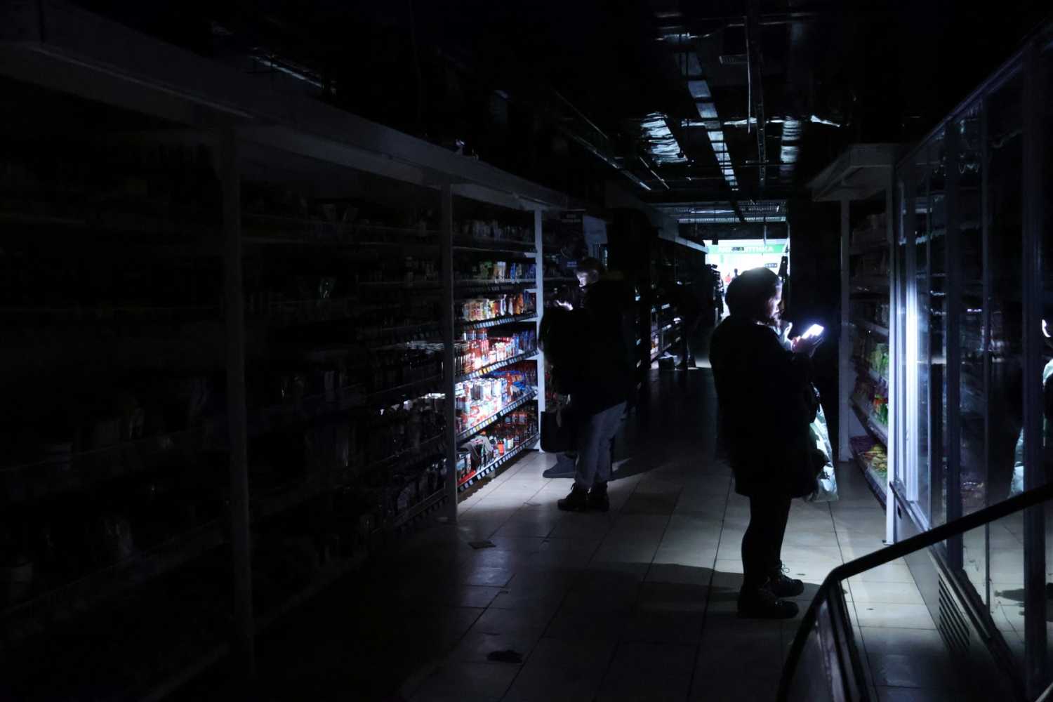 Customers use camera flashes in a supermarket during a power outage in Kyiv, Ukraine, on November 27, 2024.