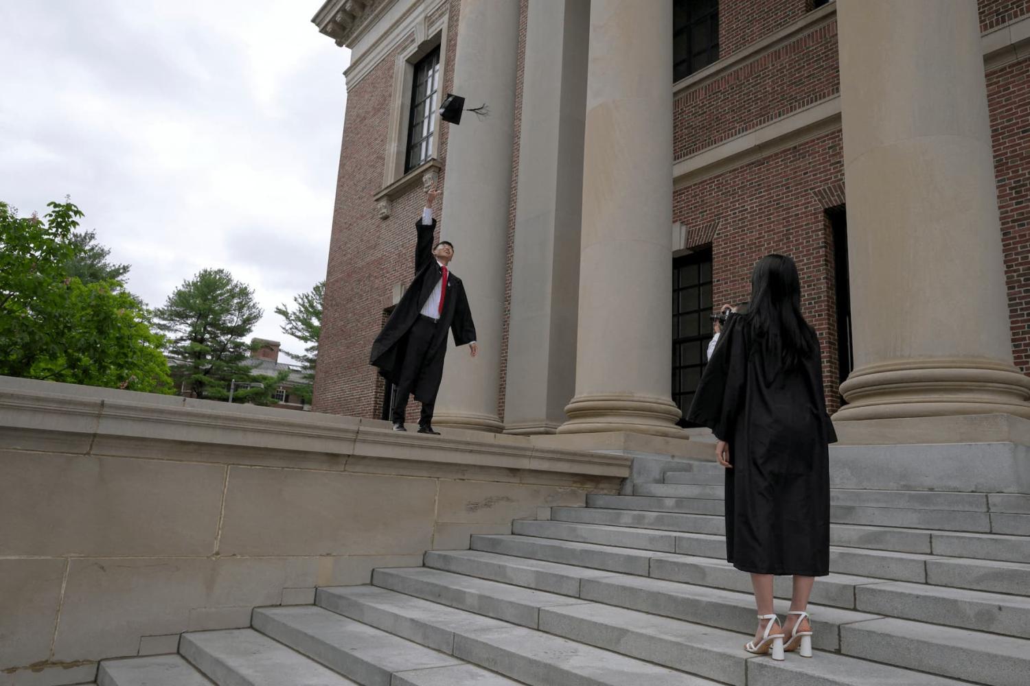Harvard College graduates, Glen Liu of Texas and Iris Lang of Florida, take graduation photos on the campus of Harvard University in Cambridge, Massachusetts, U.S., on May 23, 2025.