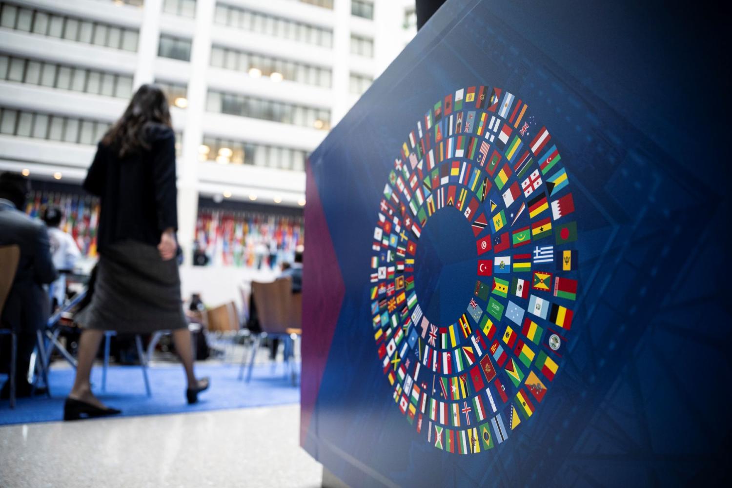 The logo of the IMF-World Bank Annual meetings in the foreground while a woman walks away in the background
