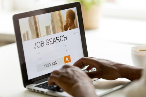 Black man browsing work opportunities online using job search computer app, black jobless seeker looking for new vacancies on website page at laptop screen, recruitment concept, rear close up view