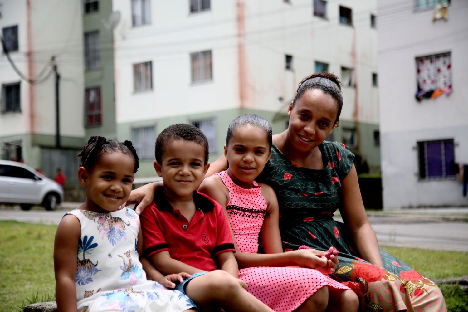 A mother sits with her three children outside an apartment complex