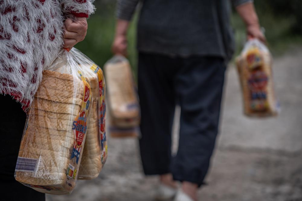 Kharkiv, Ukraine – June 21, 2025. People carry food aid packages and loaves of bread distributed by volunteers. Humanitarian assistance continues amid ongoing conflict.
