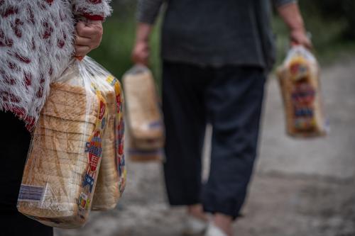 Kharkiv, Ukraine – June 21, 2025. People carry food aid packages and loaves of bread distributed by volunteers. Humanitarian assistance continues amid ongoing conflict.