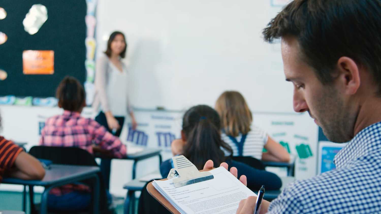A middle school principal observes and evaluates a teacher during an active classroom lesson.