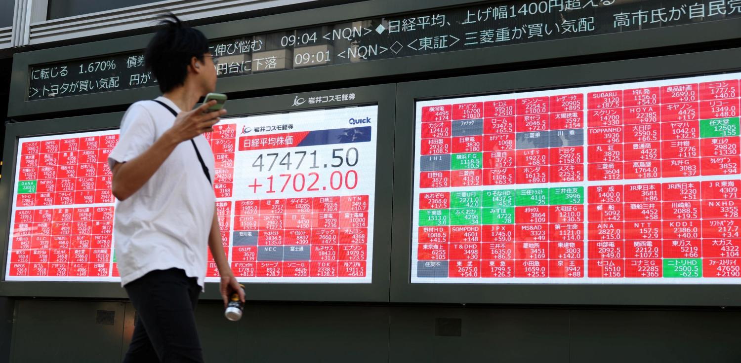 A man looks at a stock price board as he walks past