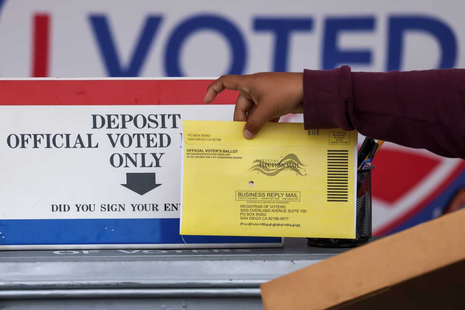 A poll worker places a mail-in ballot envelope into an official ballot drop box during the California gubernatorial recall election in San Diego in September 2021.