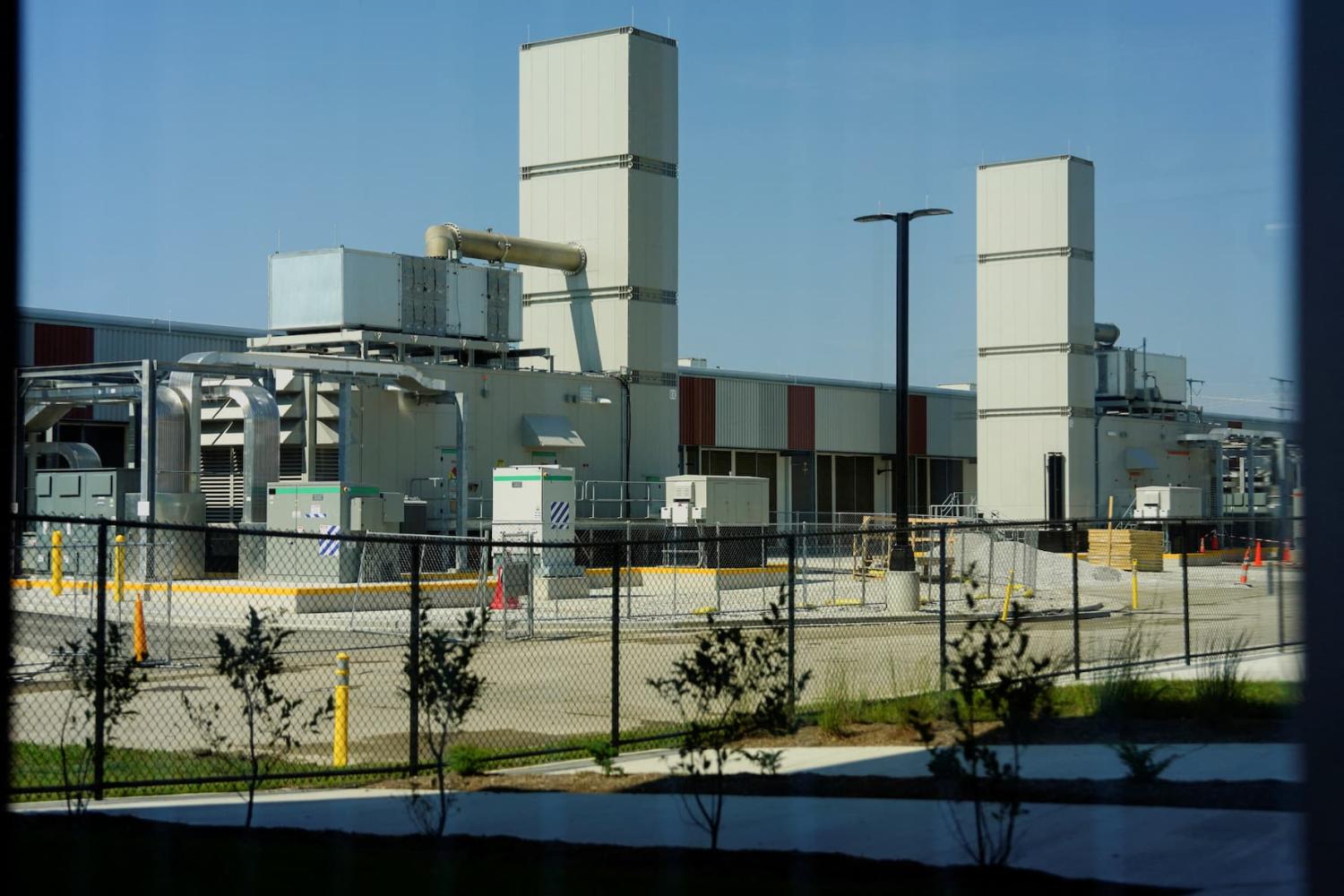 A photo of the side of a data center with two tall towers and other mechanical equipment.