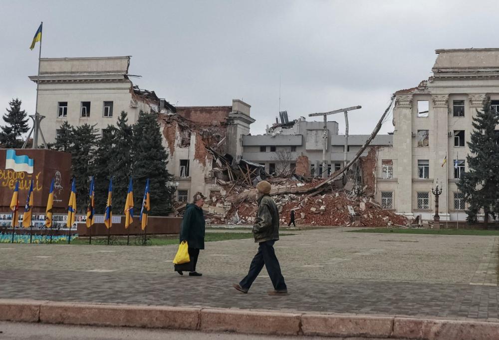 People walk near a building hit during a Russian military strike, amid Russia's attack on Ukraine, in the frontline city of Kherson, Ukraine, November 11, 2025.