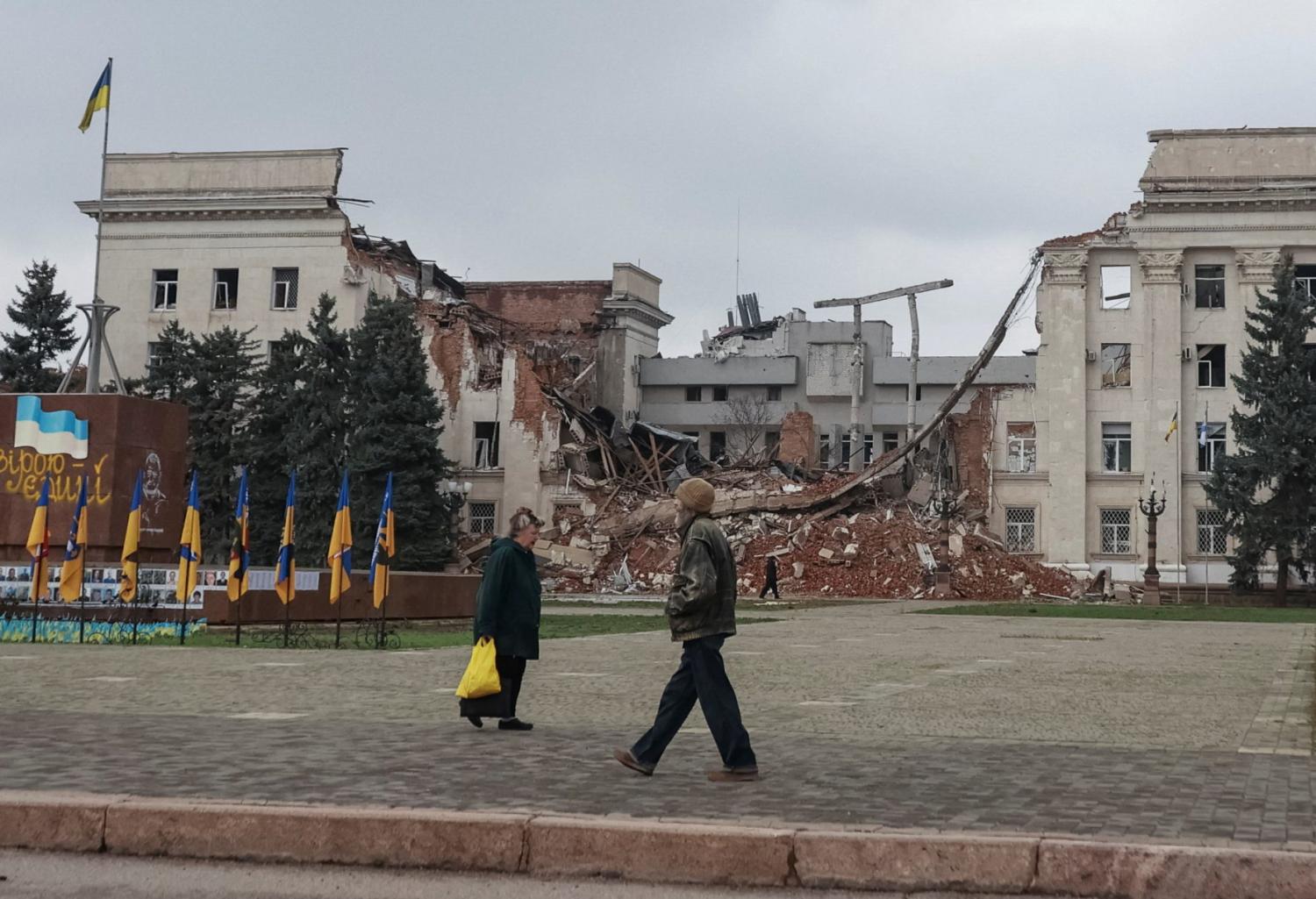 People walk near a building hit during a Russian military strike, amid Russia's attack on Ukraine, in the frontline city of Kherson, Ukraine, November 11, 2025.
