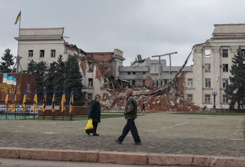 People walk near a building hit during a Russian military strike, amid Russia's attack on Ukraine, in the frontline city of Kherson, Ukraine, November 11, 2025.