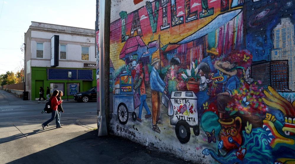 Pedestrians pass a Little Village mural in Chicago, Oct. 30, 2025